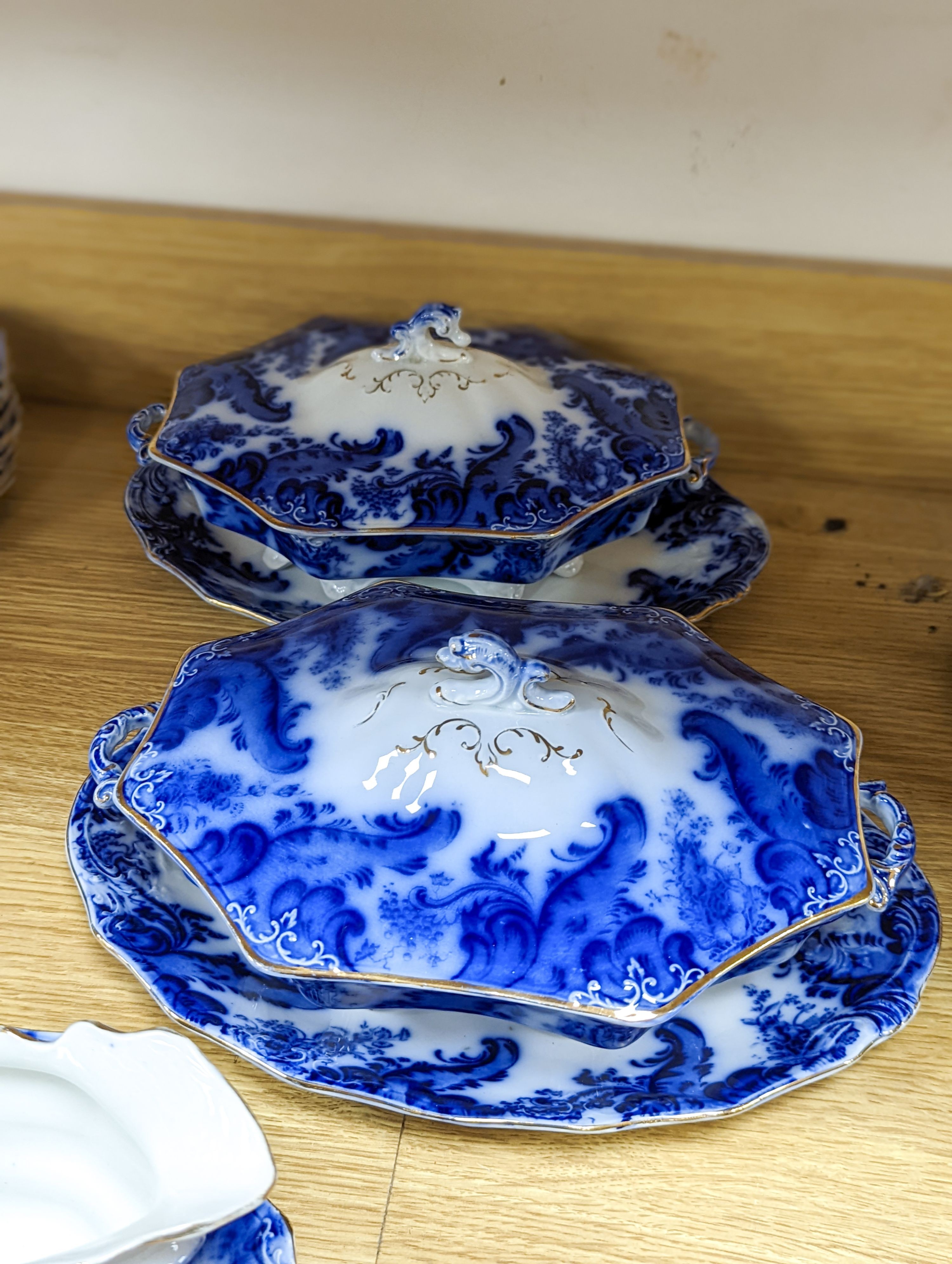 A W. H. Grindley Argyle pattern flow blue dinner service, c.1900 mostly for 12 place settings, two sauce tureens, covers and stands, two vegetable tureens and covers, two gravy boats, and six graduated meat dishes